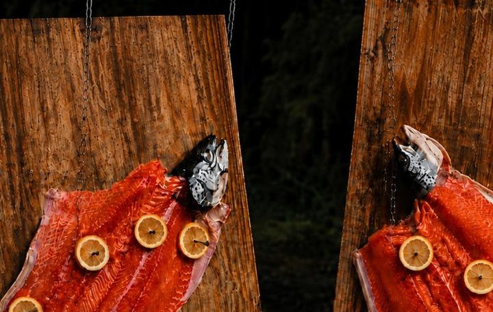 Salmão pranchado com rodelas de limão assando na tábua